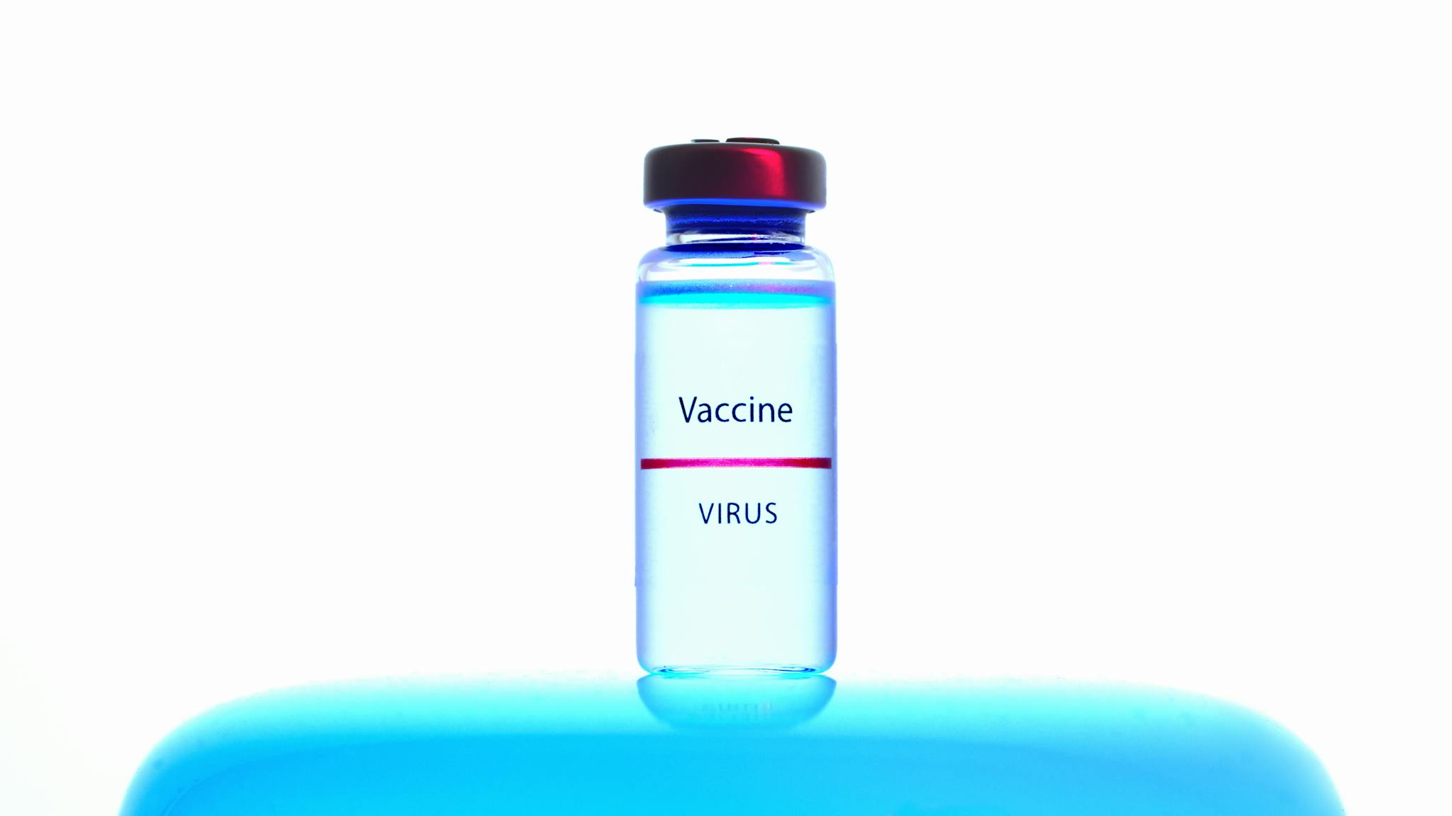 Close-up of a vaccine vial against a bright blue background, symbolizing medical research.